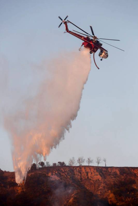 A helicopter drops water to put out hotspots in Simi Valley, Calif., Wednesday, Oct. 30, 2019. ...
