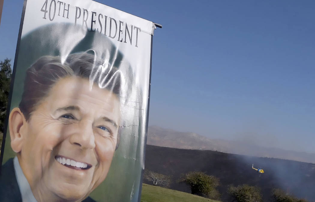 A banner hangs at the entrance to the Ronald Reagan Presidential Library as as a helicopter fli ...