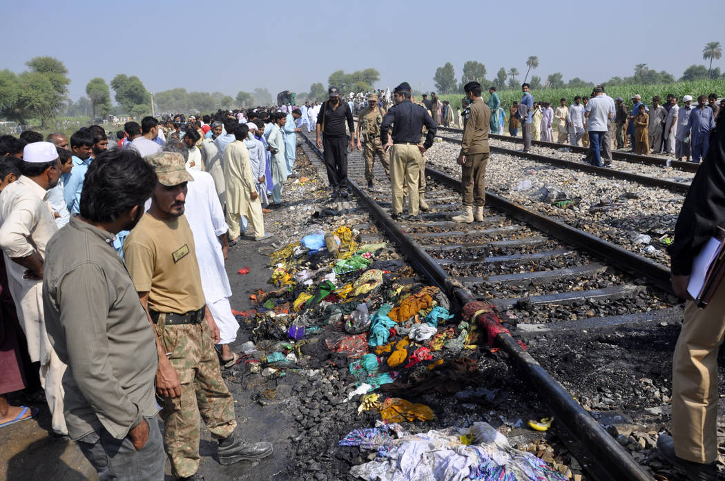 Pakistani soldiers and officials examine a train damaged by a fire in Liaquatpur, Pakistan, Thu ...