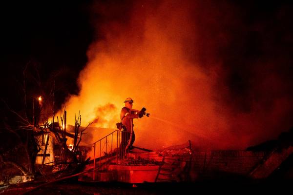 Firefighter Jesse Sparks mops up at a destroyed home as the Hillside Fire burns in San Bernardi ...
