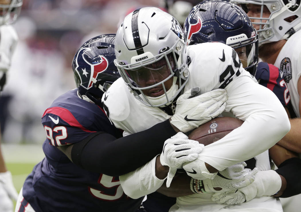Oakland Raiders running back Josh Jacobs (28) is hit by Houston Texans nose tackle Brandon Dunn ...