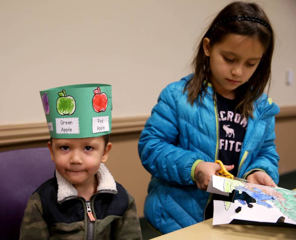 Ivan Alulema, 3, dons the "life cycle hat" he made with his sister Daria Alulema, 8, ...