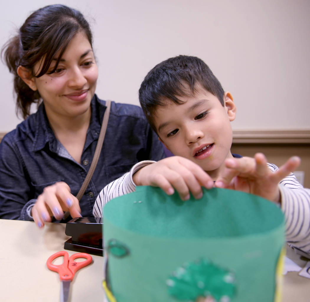 Christian Falcon, 3, works on his "life cycle hat" with his mom Berenice Falcon duri ...