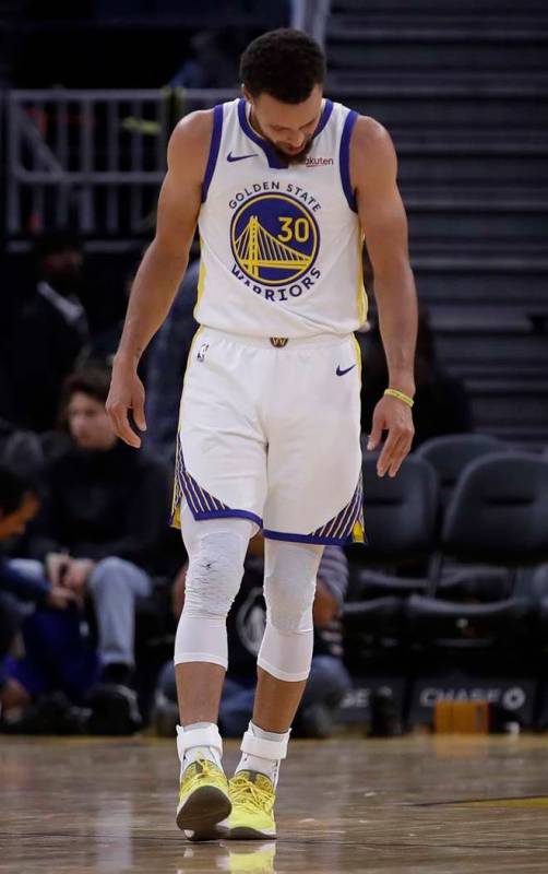 Golden State Warriors' Stephen Curry looks at his left hand after Phoenix Suns' Aron Baynes fel ...