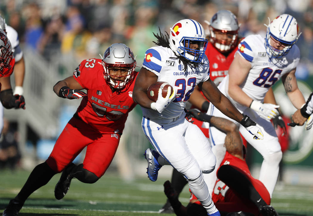 Colorado State running back Marcus McElroy, front, runs for a long gain with UNLV linebacker Fa ...