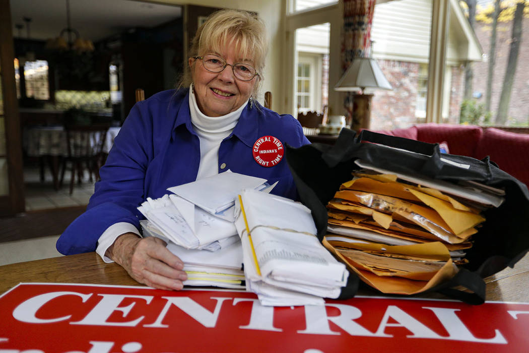 Sue Dillon poses in her home in Carmel, Ind., with some of the petitions gathered to change Ind ...