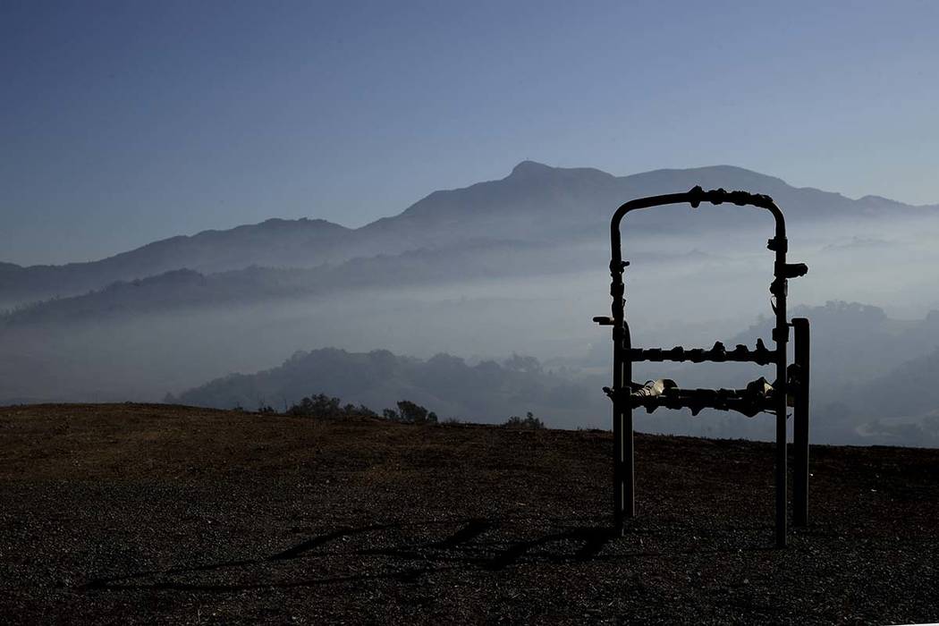 A charred lawn chair overlooks a valley filled with smoke from the Kincade Fire near Healdsburg ...