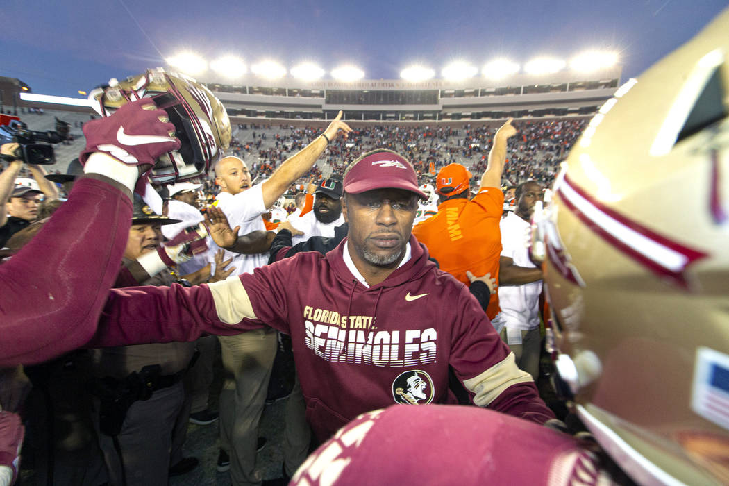 Florida State head coach Willie Taggart, center, tries to separate his team from the Miami team ...