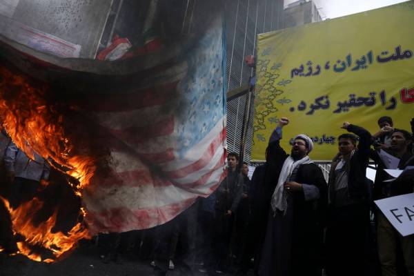 Iranian demonstrators chant slogans as they set fire a representation a makeshift U.S. flag dur ...