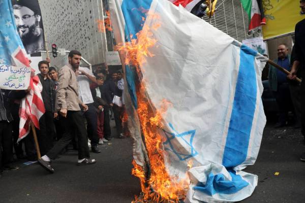 Demonstrators set fire to a makeshift Israeli flag during an anti-U.S. annual rally in front of ...