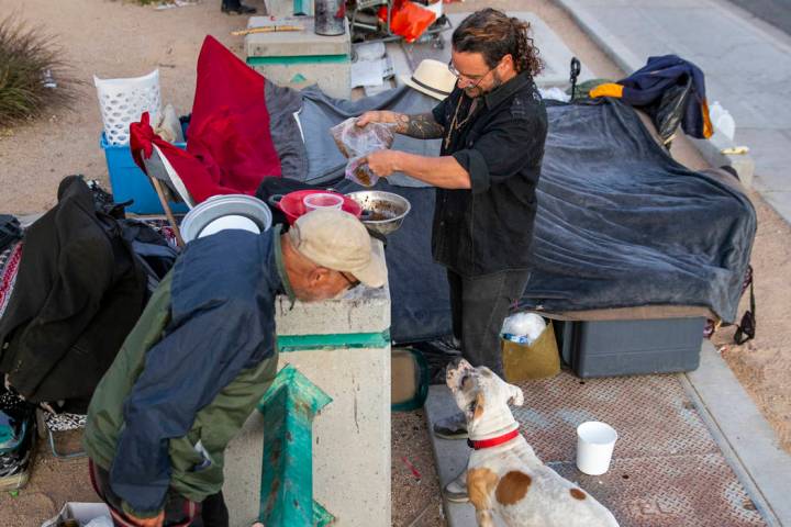 Kit Rogers, left, talks to Karma the dog as her owner James Miller pours her some dinner at a h ...