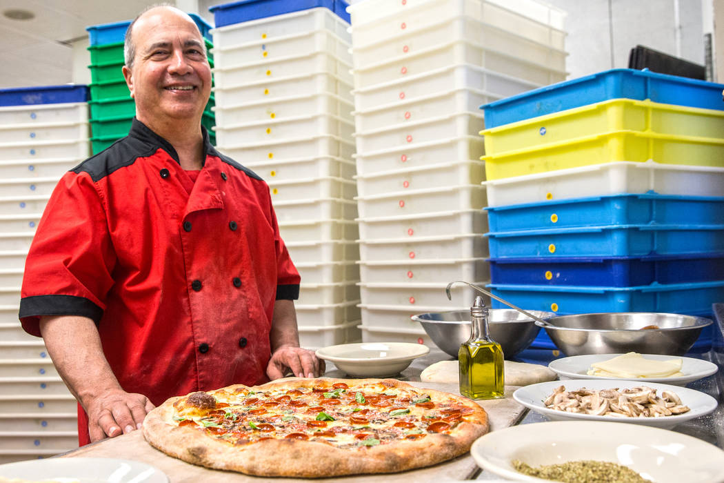 Chef/co-owner John Arena adds fresh basil to an Olde New York specialty pizza, with dozens of t ...