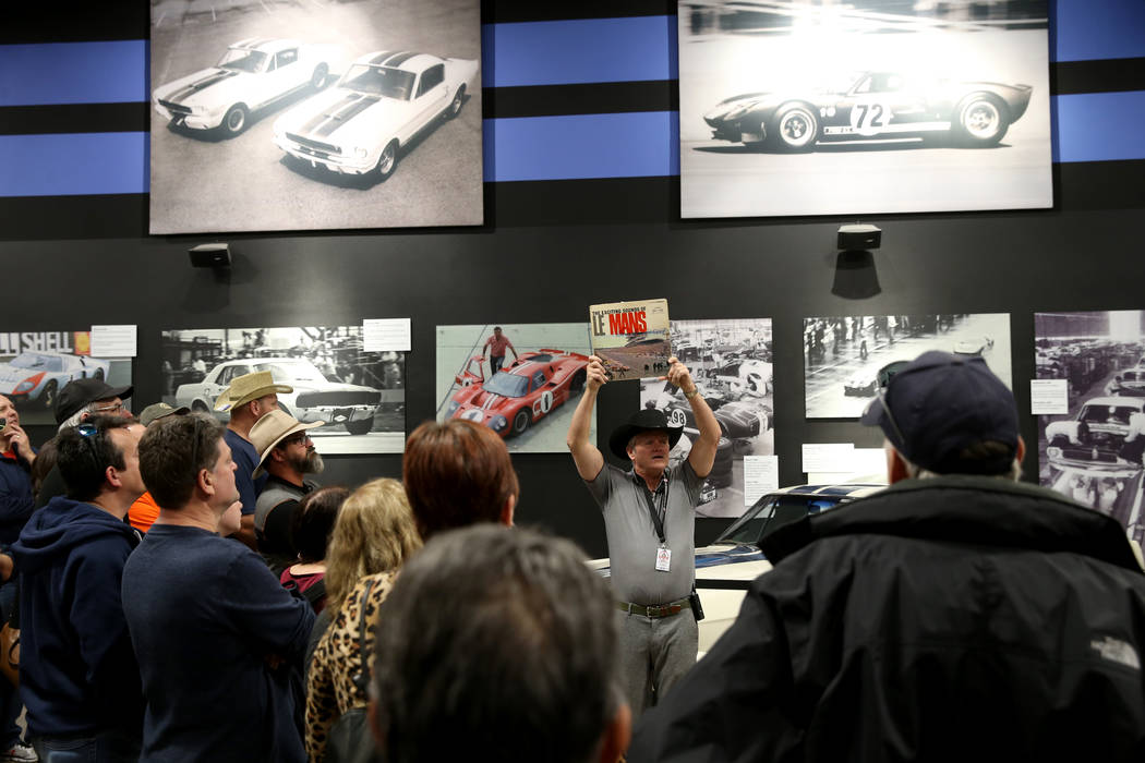 Tour guide Mike Dempsey shows an album cover featuring a photo of the 1966 La Mans race that wa ...