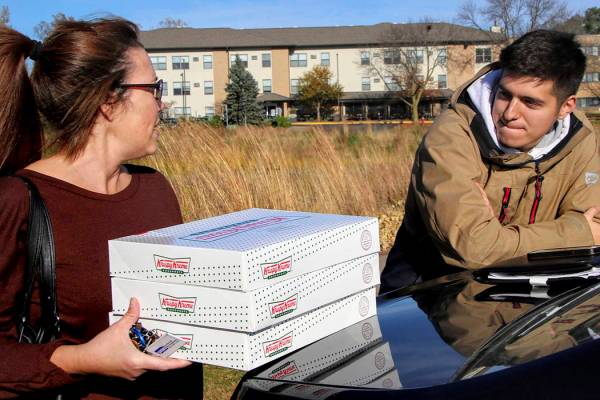 In this Saturday, Oct. 26, 2019 photo, Catherine Newton, left, buys three boxes of Krispy Kreme ...