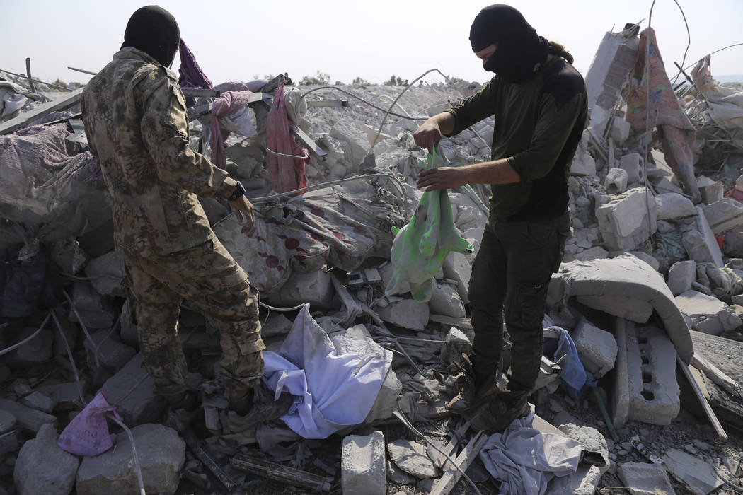 FILE - In this Oct. 27, 2019, file photo, people look at a destroyed houses near the village of ...