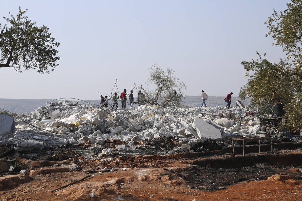 FILE - In this Oct. 27, 2019, file photo, people look at a destroyed houses near the village of ...