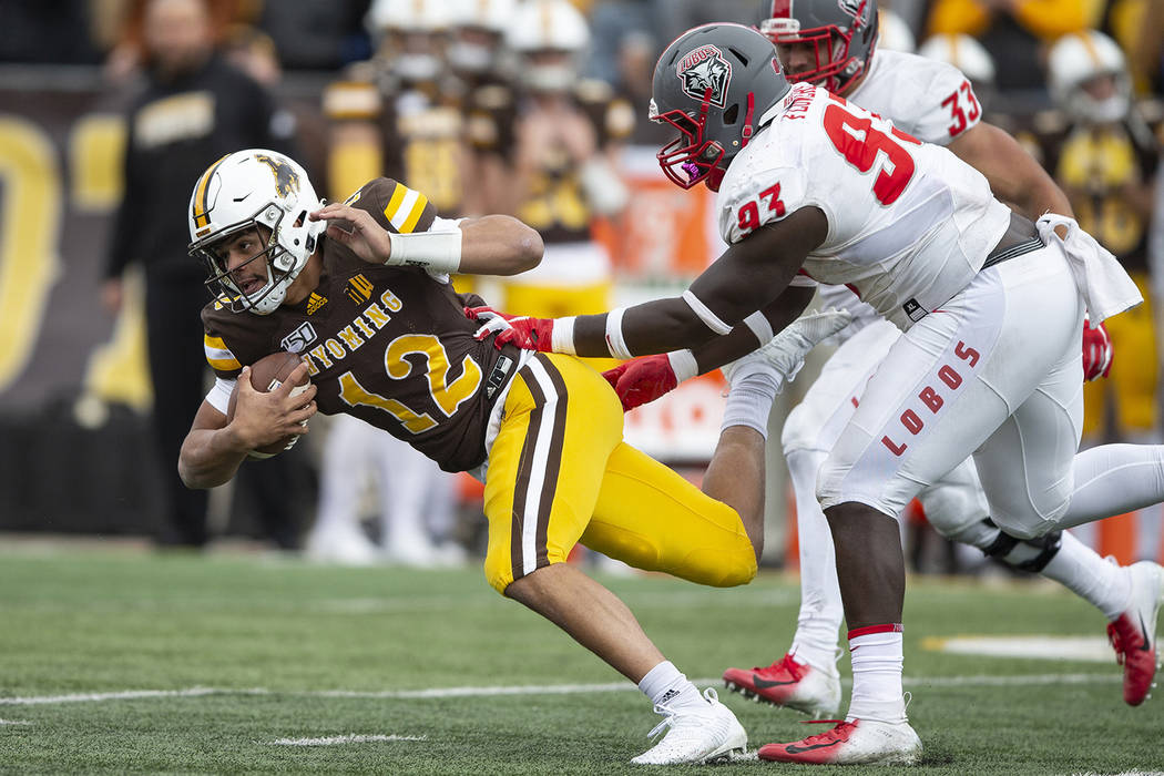 Wyoming quarterback Sean Chambers runs for yardage as New Mexico defenseman Nahje Flowers pursu ...