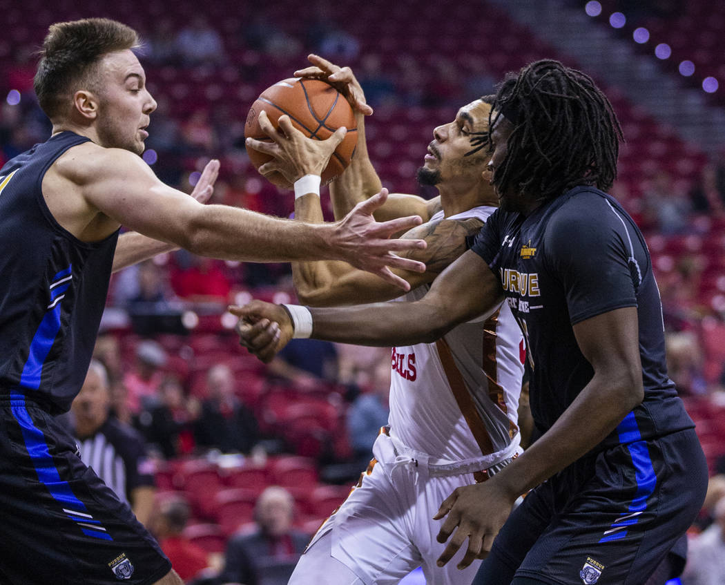 UNLV Rebels guard Elijah Mitrou-Long (55, center) attempts to drive the lane between Purdue For ...