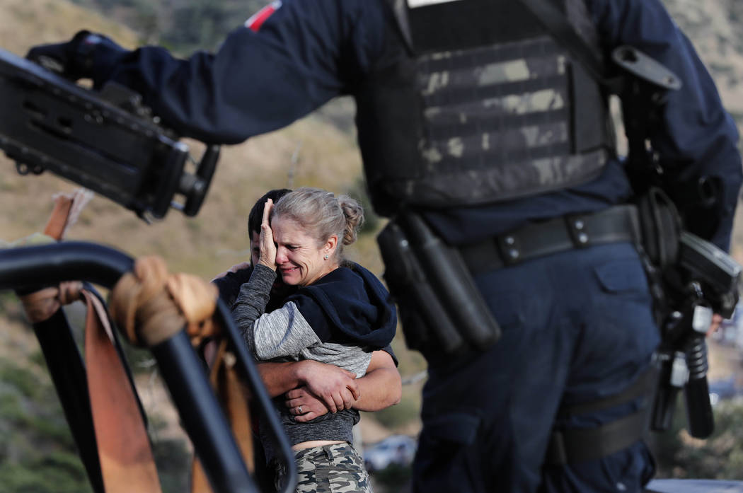 Framed by heavily armed Mexican authorities, relatives of the LeBaron family mourn at the site ...