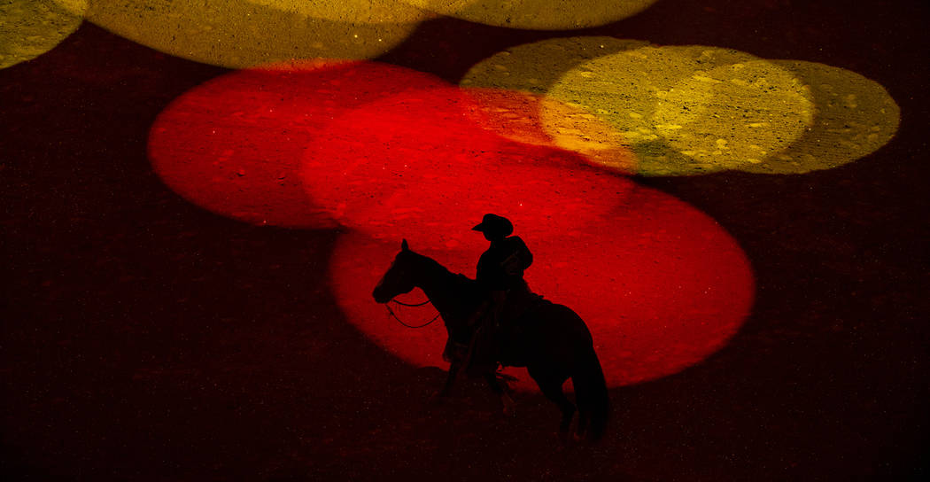 Safety man Derrick Begay is bathed in colored lights as during the opening ceremonies of PBR Wo ...