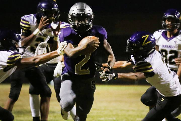 Silverado High's running back Aginae Cunningham (2) scrambles away from Durango High defense as ...