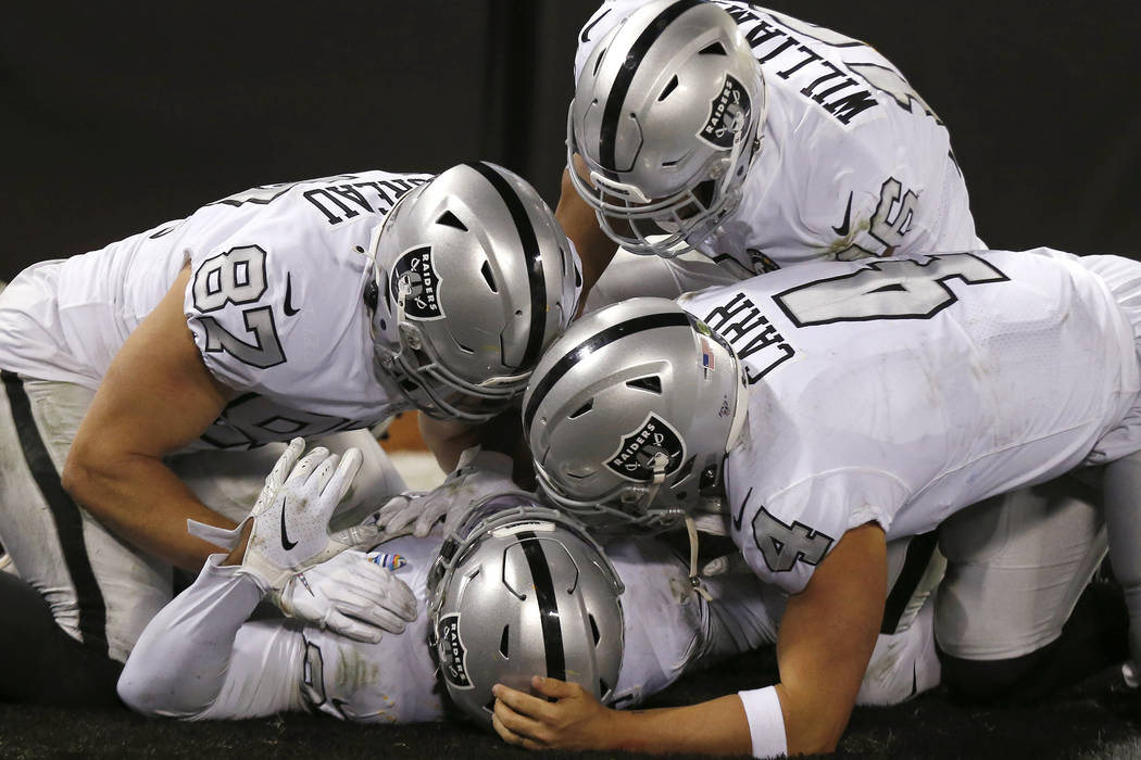 Oakland Raiders running back Josh Jacobs, bottom, is congratulated by teammates after scoring a ...