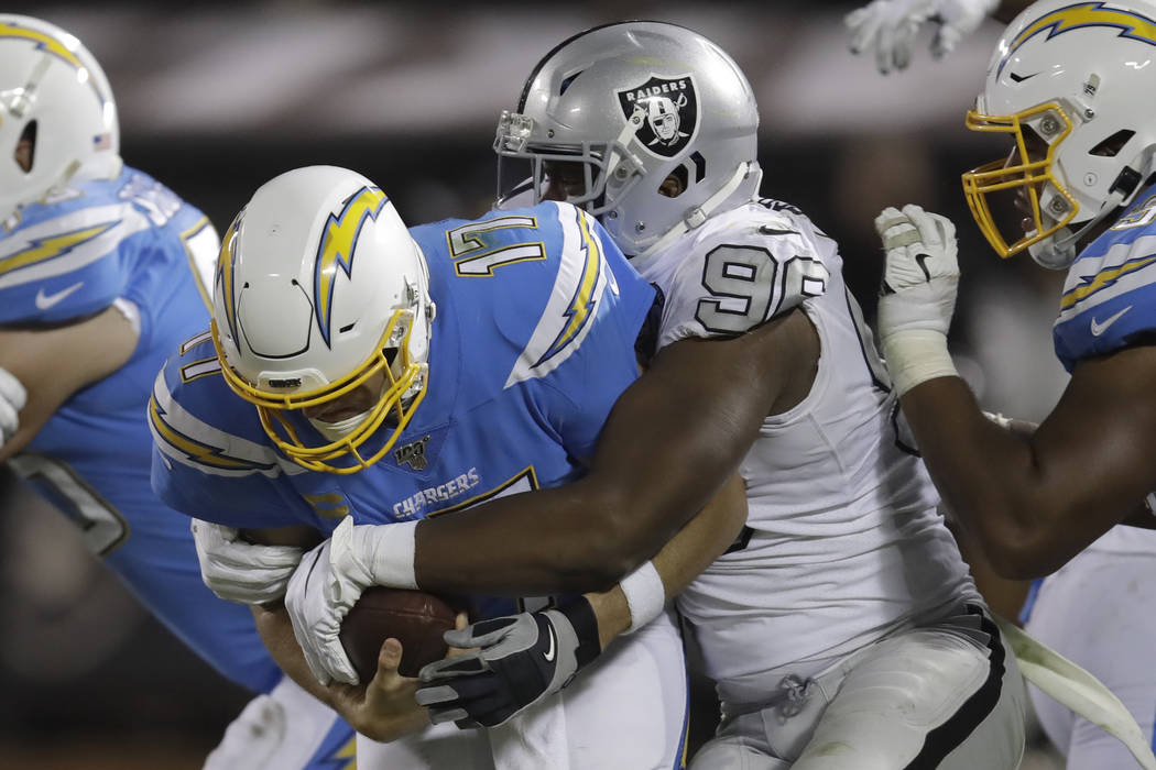 Los Angeles Chargers quarterback Philip Rivers (17) is tackled by Oakland Raiders defensive end ...