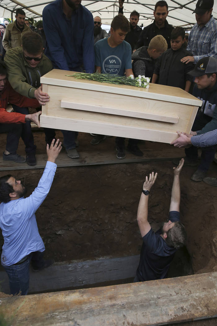 The coffin that contains the remains of 12-year-old Howard Jacob Miller Jr. is lowered into a g ...