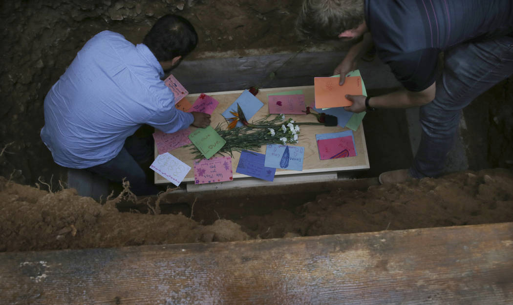 Men arrange personal notes on the coffin that contains the remains of 12-year-old Howard Jacob ...