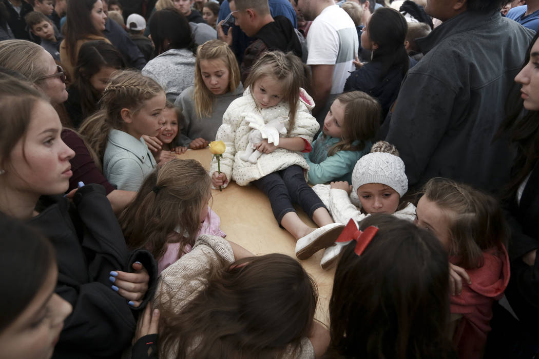 A child sits on top of a coffin as family and friends pay their final respects to Rhonita Mille ...