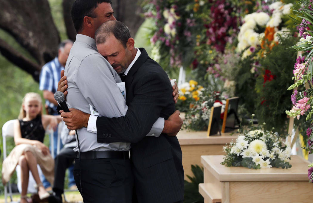 Men embrace next to the coffins of Dawna Ray Langford, 43, and her sons Trevor, 11, and Rogan, ...