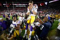 LSU quarterback Joe Burrow (9) is carried by LSU nose tackle Tyler Shelvin (72) after an NCAA f ...