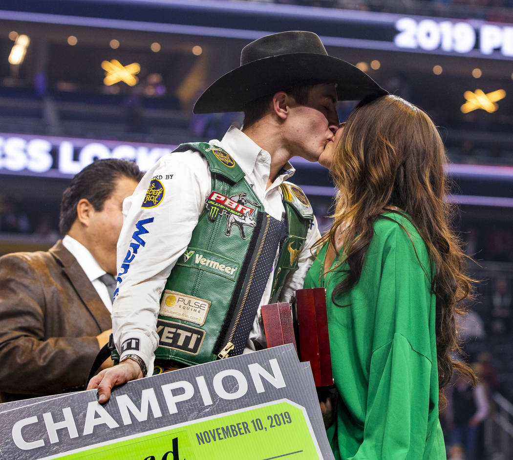 Jess Lockwood kisses his wife Hailey on stage after being awarded the 2019 PBR World Finals Cha ...