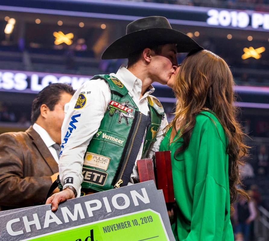 Jess Lockwood kisses his wife Hailey on stage after being awarded the 2019 PBR World Finals Cha ...