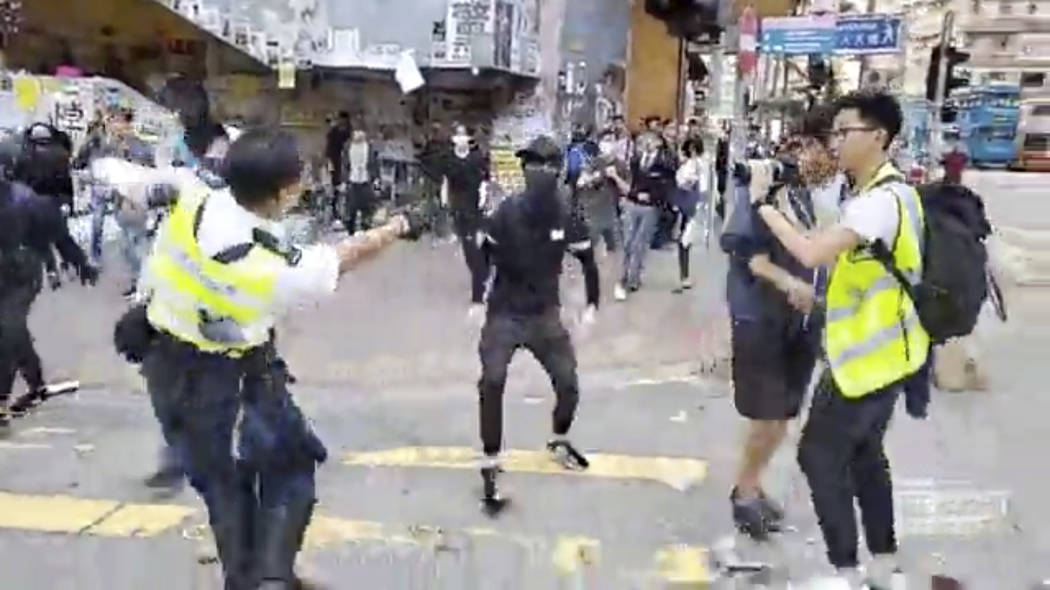 In this image made from video, a police officer, left, prepares to shoot a protester, center, i ...