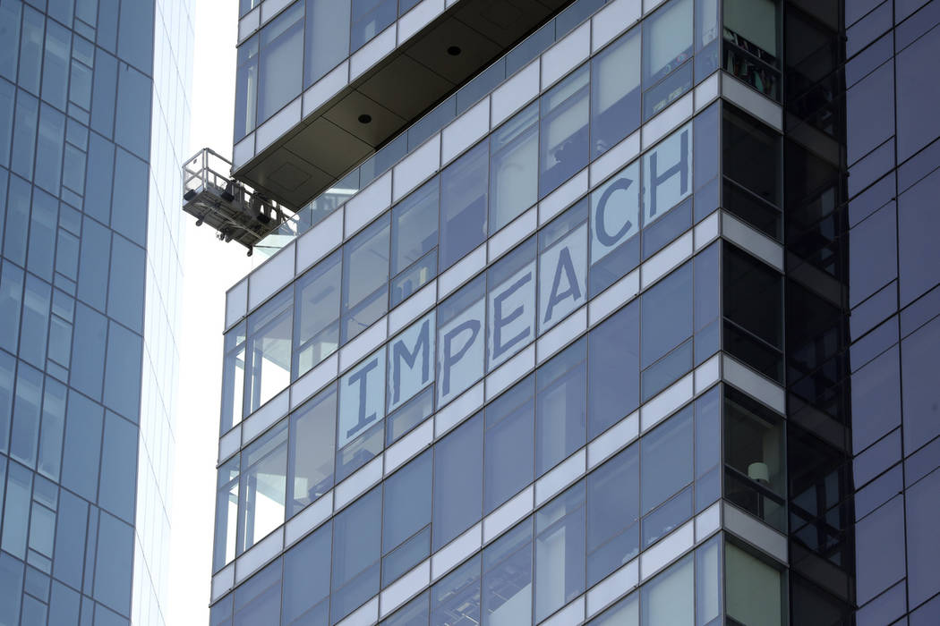 A sign spelling out the word 'impeach' is displayed in a building overlooking the site where Pr ...