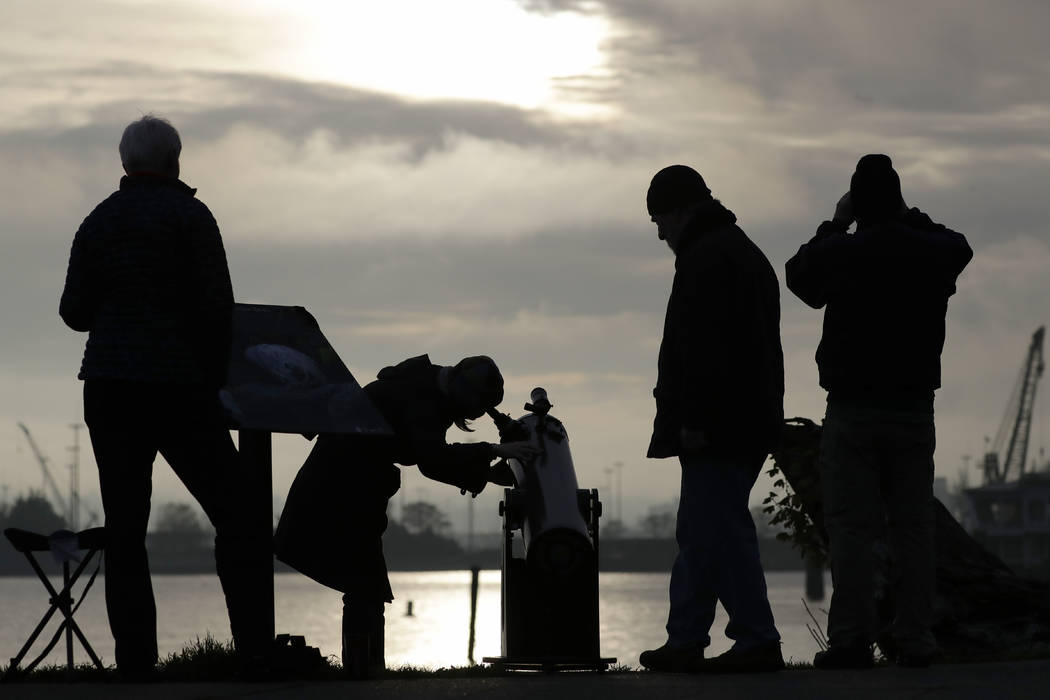 Viewers look on during a brief break in the clouds to see a transit of the planet Mercury as it ...