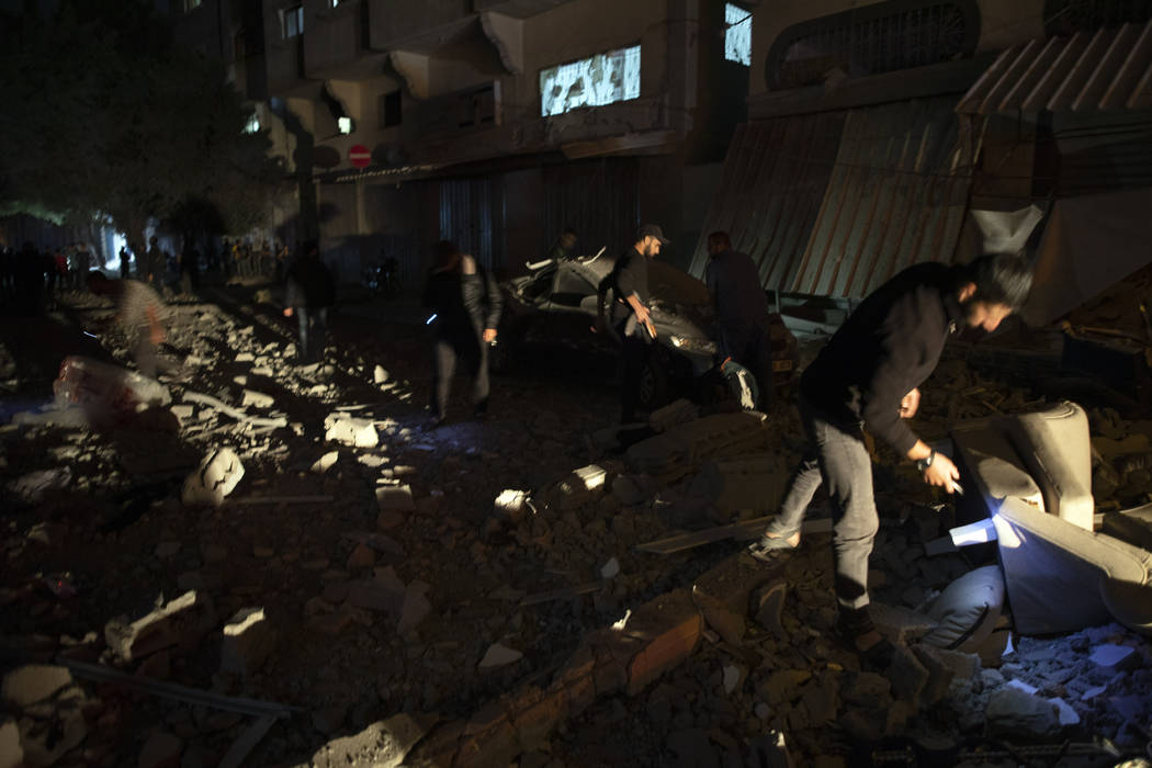 Palestinians check the damage of a house targeted by Israeli missile strikes in Gaza City, Tues ...