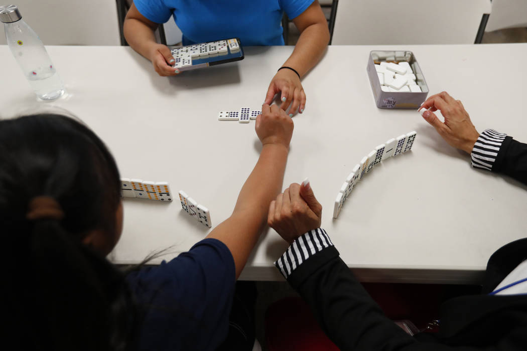 In this Sept. 24, 2019, photo, girls play dominos with a staff member at a shelter for migrant ...