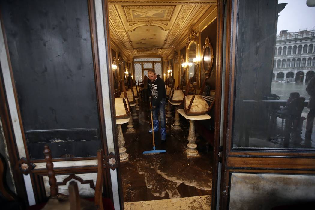 A man cleans water out of the historical Florian cafe, in Venice, Wednesday, Nov. 13, 2019. The ...