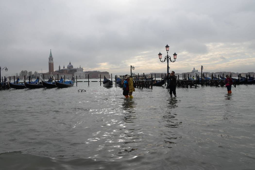People walk in high water, in Venice, Italy, Wednesday, Nov. 13, 2019. The high-water mark hit ...