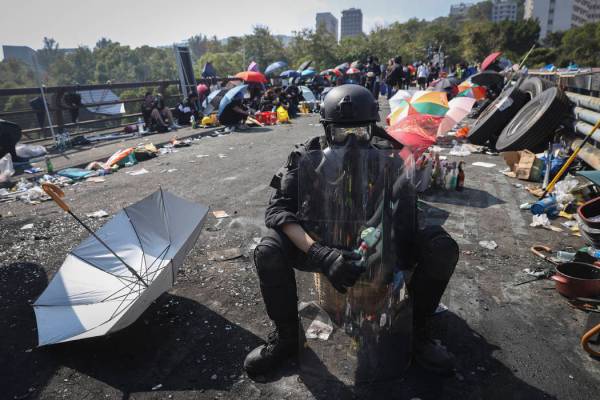 A pro-democracy protester with protection gears holds a bottle of molotov cocktail on a bridge ...