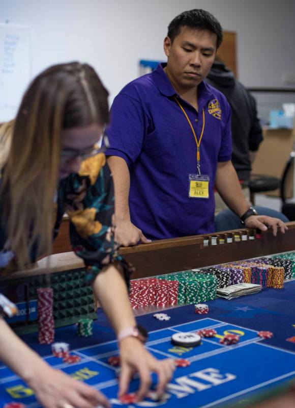 Alex Kim, executive director of Casino Education Group, center, helps Fred Chubay, right, watch ...