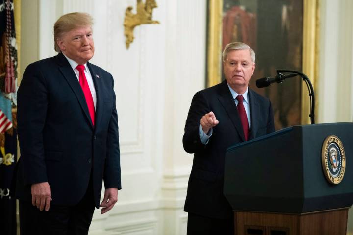 President Donald Trump listens to Sen. Lindsey Graham, R-S.C., speak during a ceremony in the E ...