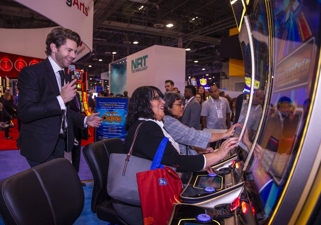 Jessica Savare, center, enjoys a turn at the Cleopatra game on display in the IGT exhibition sp ...