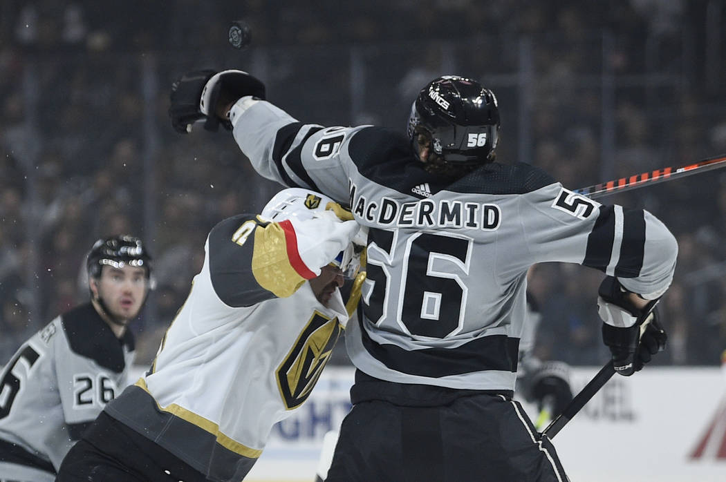 Los Angeles Kings defenseman Kurtis MacDermid, right, stretches to hit down the puck while bein ...