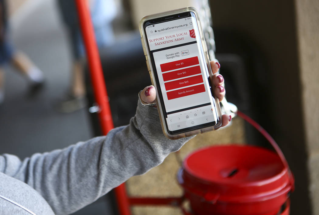 Leslee Rogers, of The Salvation Army, demonstrates how to donate with mobil phone outside of Ho ...