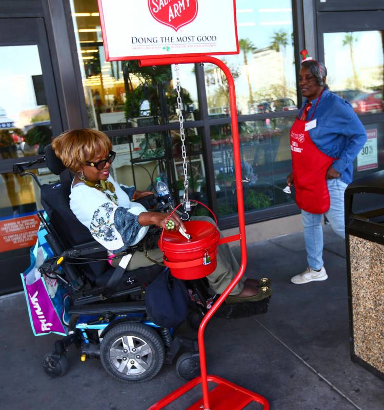 Patricia Collins puts money in the The Salvation Army red kettle as bell ringer Earline Scott, ...