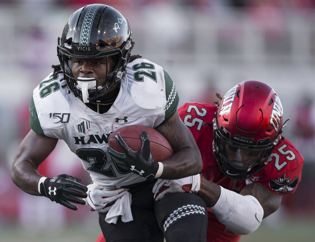 Hawaii Warriors running back Miles Reed (26) drives for the goal line with UNLV Rebels lineback ...