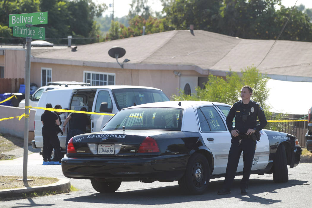 A San Diego Police officer stands in front of a home where two adults and three children died f ...
